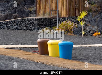 Nahaufnahme von bunten Mülltonnen zum Recycling an einem Sandstrand Stockfoto