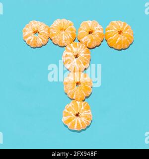 Kreatives Layout des Buchstabens T aus geschälten Mandarinen auf blauem Hintergrund. Flatlay. Stockfoto