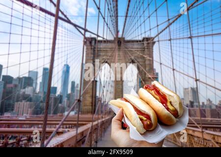 Halten von zwei Hot Dogs in NYC auf der Brooklyn Bridge . Stockfoto