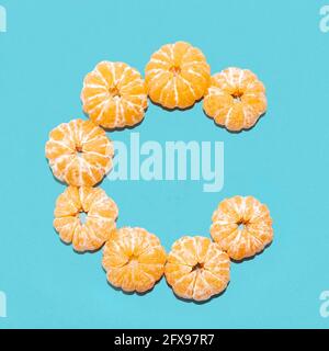 Kreatives Layout des Buchstabens C aus geschälten Mandarinen auf blauem Hintergrund. Flatlay. Stockfoto