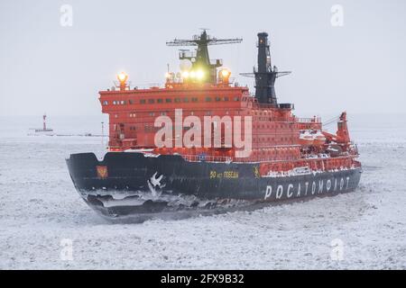 Sabetta, Region Tjumen, Russland - 4. April 2021: Der 50 ließ Pobedy Eisbrecher zieht in Eis. Bewölkt, leichter Schnee fällt. Stockfoto