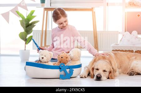 Kleines Mädchen spielen mit Seeschiff mit goldenem Retriever Hund Stockfoto