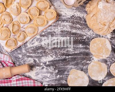 Traditionelle russische rohe Pelmeni auf einem Metalltablett mit Fleischknödeln und Zutaten. Teig und Hackfleisch Stockfoto