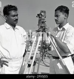 1957, historisch, zwei indische Vermesser mit einem No 1 Hilger & Watts Microptic Theodolit auf Stativ auf der Baustelle des Durgapur Steel Project, Durgapur, Westbengalen, Indien. Als präzises optisches Instrument zur Messung von Winkeln zwischen sichtbaren Punkten in der horizontalen und vertikalen Ebene wurde dieser Transittheodolit im Bau- und Infrastrukturbau ausgiebig eingesetzt. Stockfoto