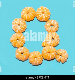 Kreatives Layout des Buchstabens Q aus geschälten Mandarinen auf blauem Hintergrund. Flatlay. Stockfoto