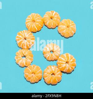 Kreatives Layout des Buchstabens G aus geschälten Mandarinen auf blauem Hintergrund. Flatlay. Stockfoto