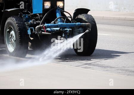 Die Gießmaschine gießt Wasser auf die Straße. Desinfektion von Straßen während der Coronavirus-Pandemie Covid-19 Stockfoto