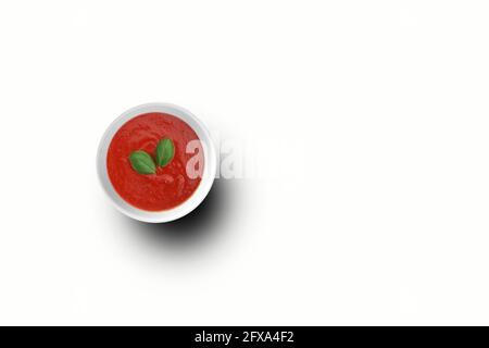 Top-up-Ansicht Tomaten Ketchup auf weiße Schüssel mit zwei Blättern . Top-Ansicht Tomaten Ketchup auf weiße Schüssel . Passend für Ihr Design-Element. Stockfoto