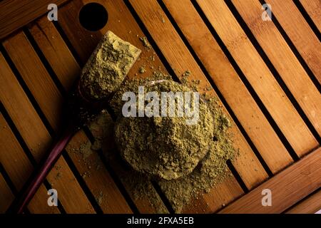 matcha, grüner Tee in Tontopf und ein Holzspatel streut Tee auf Holzhintergrund. Food Photography Stockfoto