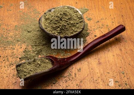 matcha, grüner Tee in Tontopf und ein Holzspatel streut Tee auf Holzhintergrund. Food Photography Stockfoto