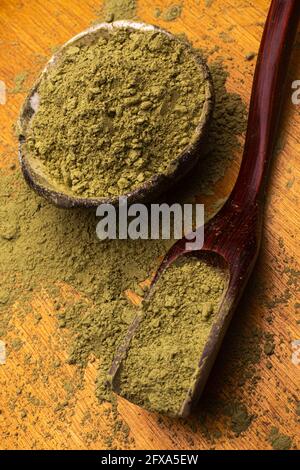 matcha, grüner Tee in Tontopf und ein Holzspatel streut Tee auf Holzhintergrund. Food Photography Stockfoto