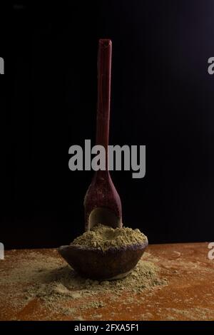 matcha, grüner Tee in Tontopf und ein Holzspatel streut Tee auf Holzhintergrund. Food Photography Stockfoto