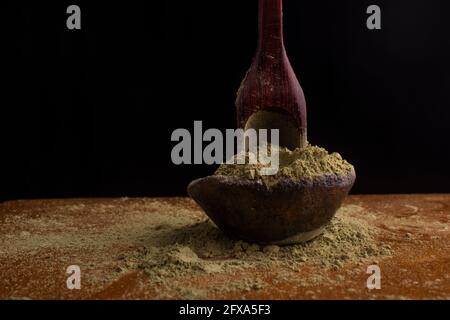 matcha, grüner Tee in Tontopf und ein Holzspatel streut Tee auf Holzhintergrund. Food Photography Stockfoto