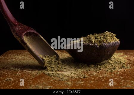 matcha, grüner Tee in Tontopf und ein Holzspatel streut Tee auf Holzhintergrund. Food Photography Stockfoto