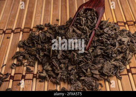 Grüner Tee und ein Holzspatel streut Tee auf hölzernen Hintergrund. Food-Fotografie Stockfoto