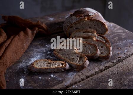 Hoher Winkel von Scheiben von frischem Roggenbrot auf gelegt Rustikaler Holztisch in der Nähe von braunem Stoff Stockfoto
