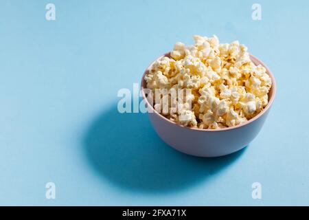 Hausgemachtes Popcorn in Minsk auf blauem Hintergrund mit hartem Schatten. Speicherplatz kopieren. Stockfoto