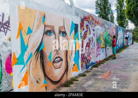 BERLIN, DEUTSCHLAND - 6. AUGUST 2017: Graffiti-Künstler malen auf einem Abschnitt der Berliner Mauer im Mauerpark. Stockfoto