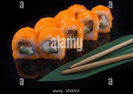 Sushi-Rolle mit fliegendem Fischrogen auf schwarzem Hintergrund Stockfoto