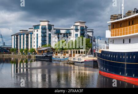 Edinburgh, Schottland, Großbritannien, 26. Mai 2021. Wetter in Großbritannien: Water of Leith Reflexionen an der Küste eines modernen Wohnblocks namens Queen's Quay, vertäute Bargen und schwimmendes Hotel mit Meeresmist Stockfoto