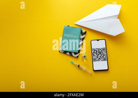 Impfstoff und Spritze covid 19 grünen Pass QR-Code auf Smartphone-Bildschirm und Papierflugzeug. Digitales Zertifikat Corona-Impfpass für freies Reisen Stockfoto