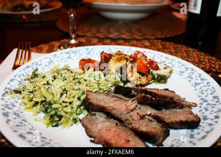 Nahaufnahme einer Portion toskanisches Steak mit Orzo, gebratenen Zucchini und Kirschtomaten. Stockfoto