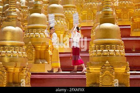 Burmesische Gläubige laufen barfuß um den Shwedagon herum Pagode trägt eine traditionelle und bunte Longyi (traditionelle burmesische Kleidung Stockfoto