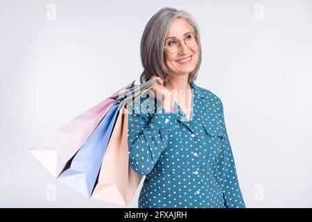 Foto-Porträt einer älteren Dame, die Taschen zum Verkauf hält Einkaufszentrum suchen Copyspace isoliert auf weißem Hintergrund Stockfoto