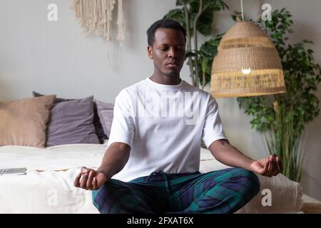 Junger afrikanischer Mann meditiert an seinem Schlafzimmer in der sitzend Morgen Stockfoto