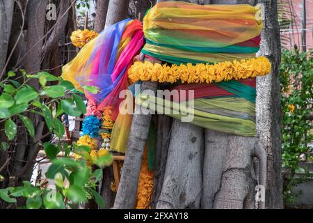 Ringelblume Blumengirlanden und Stofffarben bunt um die gewickelt Baum das bunte Tuch, das um einen Baum gebunden ist, ist das Der Glaube an den thailändischen Schurken Stockfoto