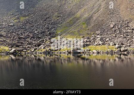 Steine spiegeln sich in der Oberfläche von Goat's Water in Cumbria, England. Stockfoto