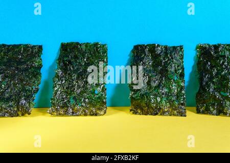 Knusprig getrocknete Seetang, Nori Chips Stück gerösteten Seetang Blatt auf einem bunten Hintergrund. Gesundes Lebensmittelkonzept. Stockfoto