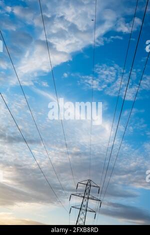 Strommast und Kabel gegen eine blaue bewölkt und hell Sky liefert häuslichen Strom für den grünen Energiebedarf an die Haushalte Stockfoto