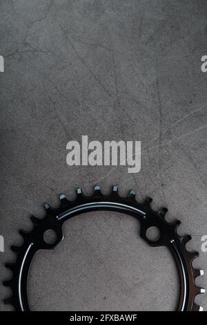 Schwarzer Stern des schmalen breiten Fahrrad-Pleuelsystems. Ein Zahnmuster eines fahrenden Fahrradstars auf schwarzem Hintergrund. Makro für dunkle Tasten Stockfoto