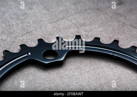 Schwarzer Stern des schmalen breiten Fahrrad-Pleuelsystems. Ein Zahnmuster eines fahrenden Fahrradstars auf schwarzem Hintergrund. Makro für dunkle Tasten Stockfoto