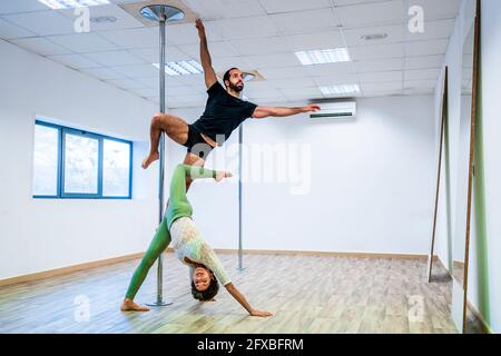 Männliche und weibliche Tänzer dehnen sich während des Übens auf der Rute im Tanzstudio Stockfoto