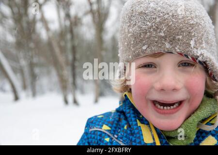 Netter Junge, der im Winter im Schnee friert Stockfoto