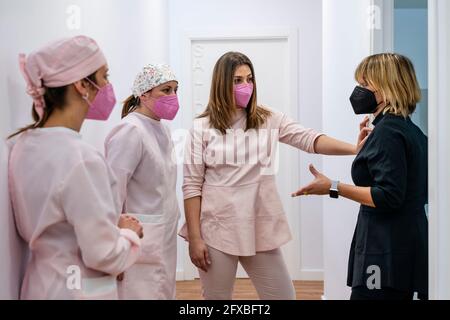 Zahnärztin gestikuliert, während sie mit Kollegen in der Klinik spricht Stockfoto