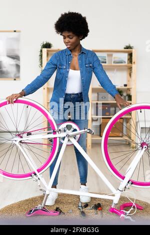 Afro-Frau mit umgedrehten Fahrrad zu Hause Stockfoto