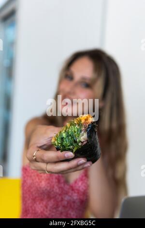 Junge Frau hält Essen im Restaurant Stockfoto