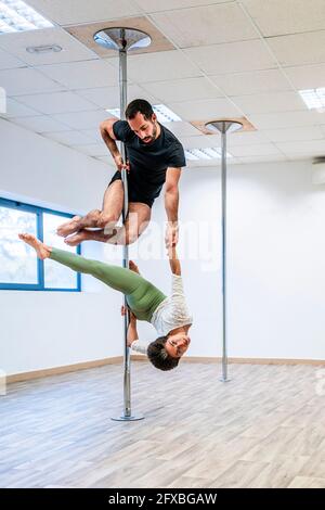 Multiethnische männliche und weibliche Akrobaten üben gemeinsam auf Rute im Tanzstudio Stockfoto