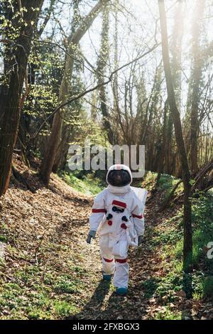 Weibliche Forscherin im Raumanzug und Helm, die auf dem Fußweg läuft Stockfoto