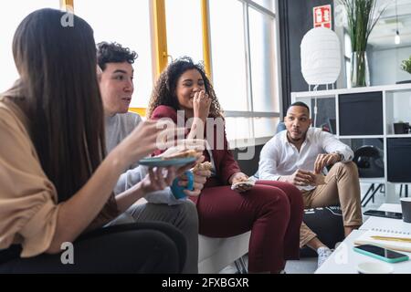 Glückliche Unternehmer beim Frühstück im Coworking-Büro Stockfoto