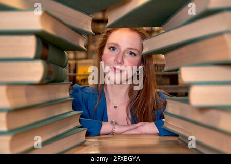 Schöne Frau mit langen Haaren durch Stapel von Büchern gesehen Stockfoto