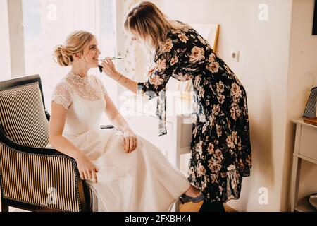 Make-up Artist, der während der Hochzeit Lippenstift auf die angeregte Braut aufklebt Stockfoto