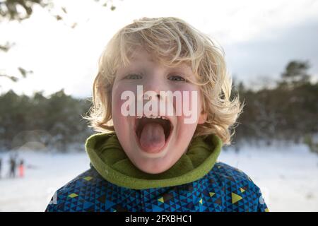 Blonde Haare Junge ragt aus Zunge im Winter Stockfoto