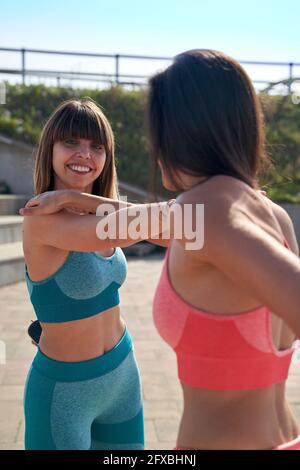 Weibliche Athleten beim Stretching an sonnigen Tagen Stockfoto