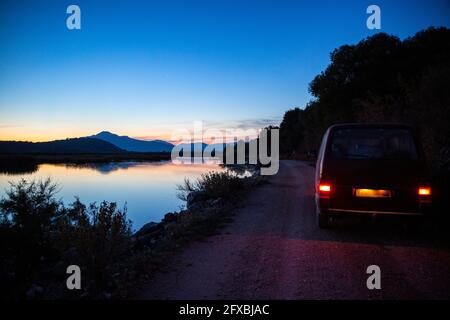 Kleinbus, der in der Abenddämmerung auf einer unbefestigten Straße im Amvrakikos Wetlands National Park fährt Stockfoto