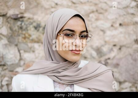 Schöne Frau mit Kopftuch und Brille vor der Wand Stockfoto