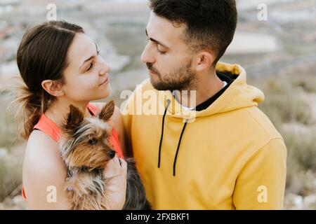 Junger Mann, der die Frau ansieht, die Hund in der Hand hält Stockfoto